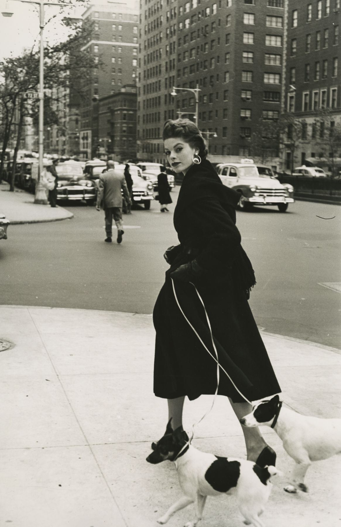 Frances McLaughlin-Gill  Model Walking Two Jack Russel Terriers, NYC, 1953  Gelatin silver print; printed c.1953  16 1/4 x 10 3/4 inches