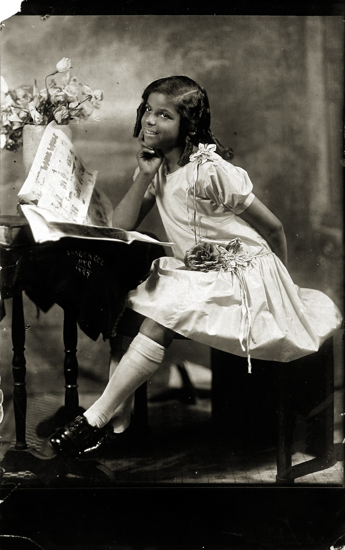 Untitled (young girl seated at desk with newspaper), 1927  Gelatin silver print on carte postale; printed c.1927  6 3/4 x 5 inches