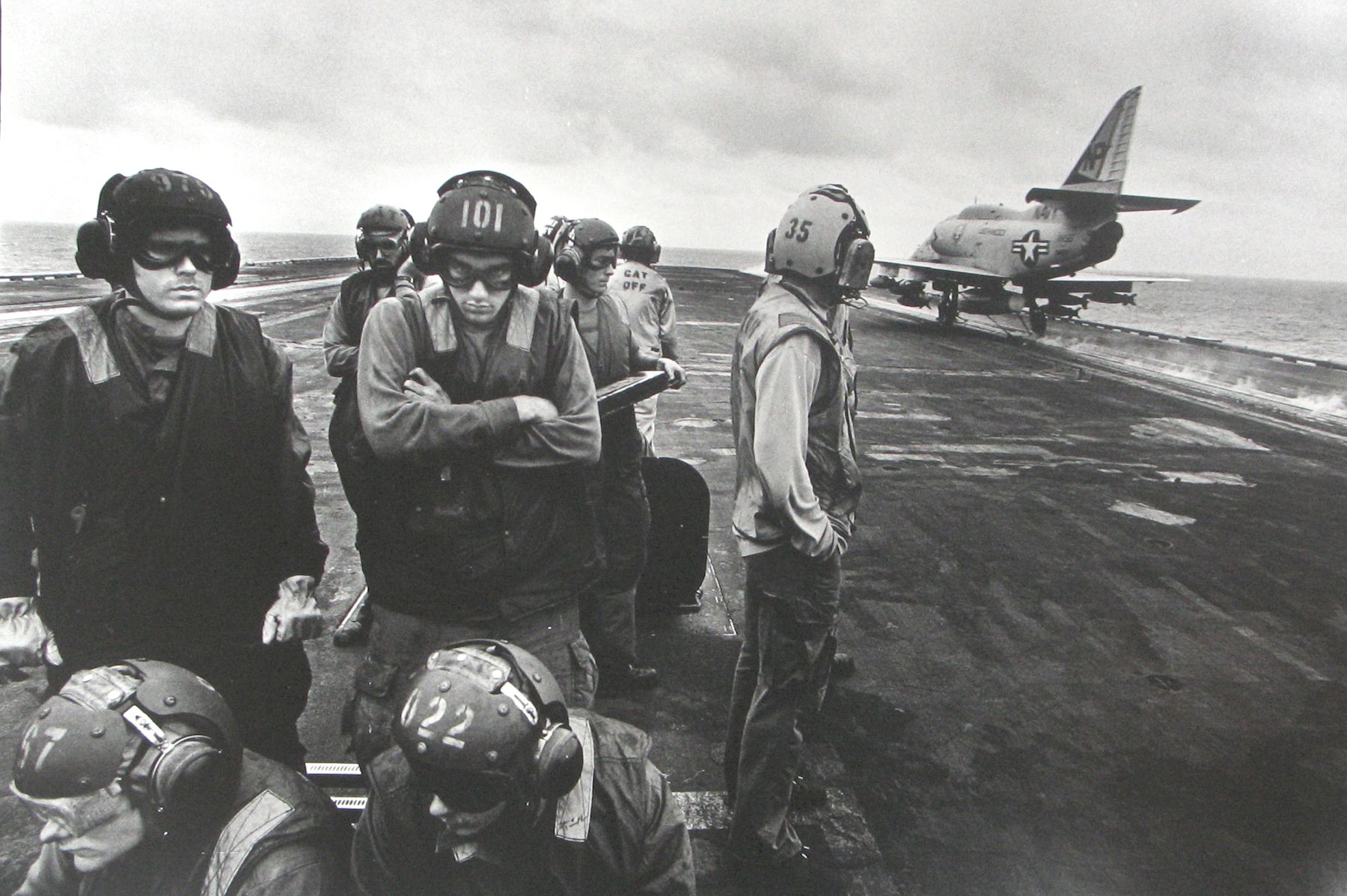 Philip Jones Griffiths - Bomb-laden planes are catapulted off the deck. Intended for emergency use in far-off conflicts, carriers are wasteful of men and machines, 1971 - Howard Greenberg Gallery