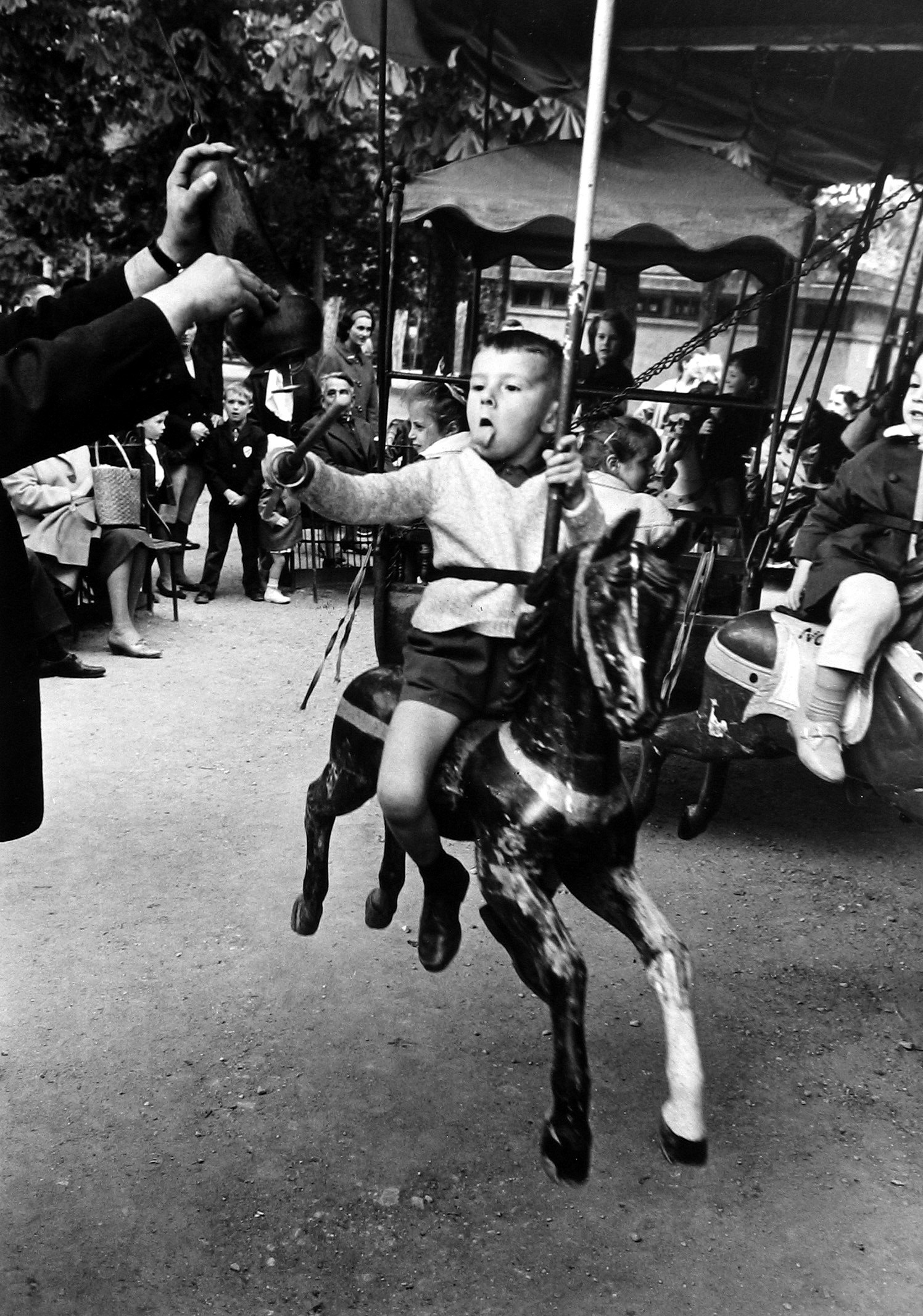 Alfred Eisenstaedt - Boy with tongue out spearing brass ring, Luxumbourg Garden, Paris, 1964 - Howard Greenberg Gallery