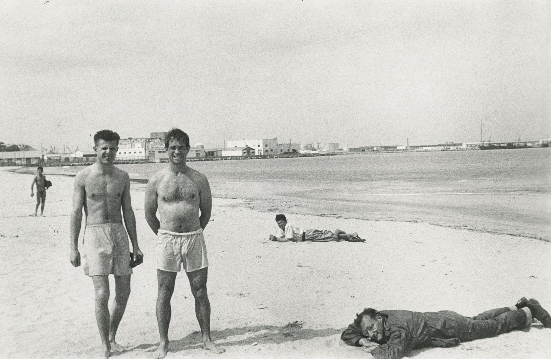 Allen Ginsberg - Peter Orlovsky and Jack Kerouac squinting in morning sunlight, William Burroughs prone observing in his olive green army jacket, Tangier, 1957 - Howard Greenberg Gallery