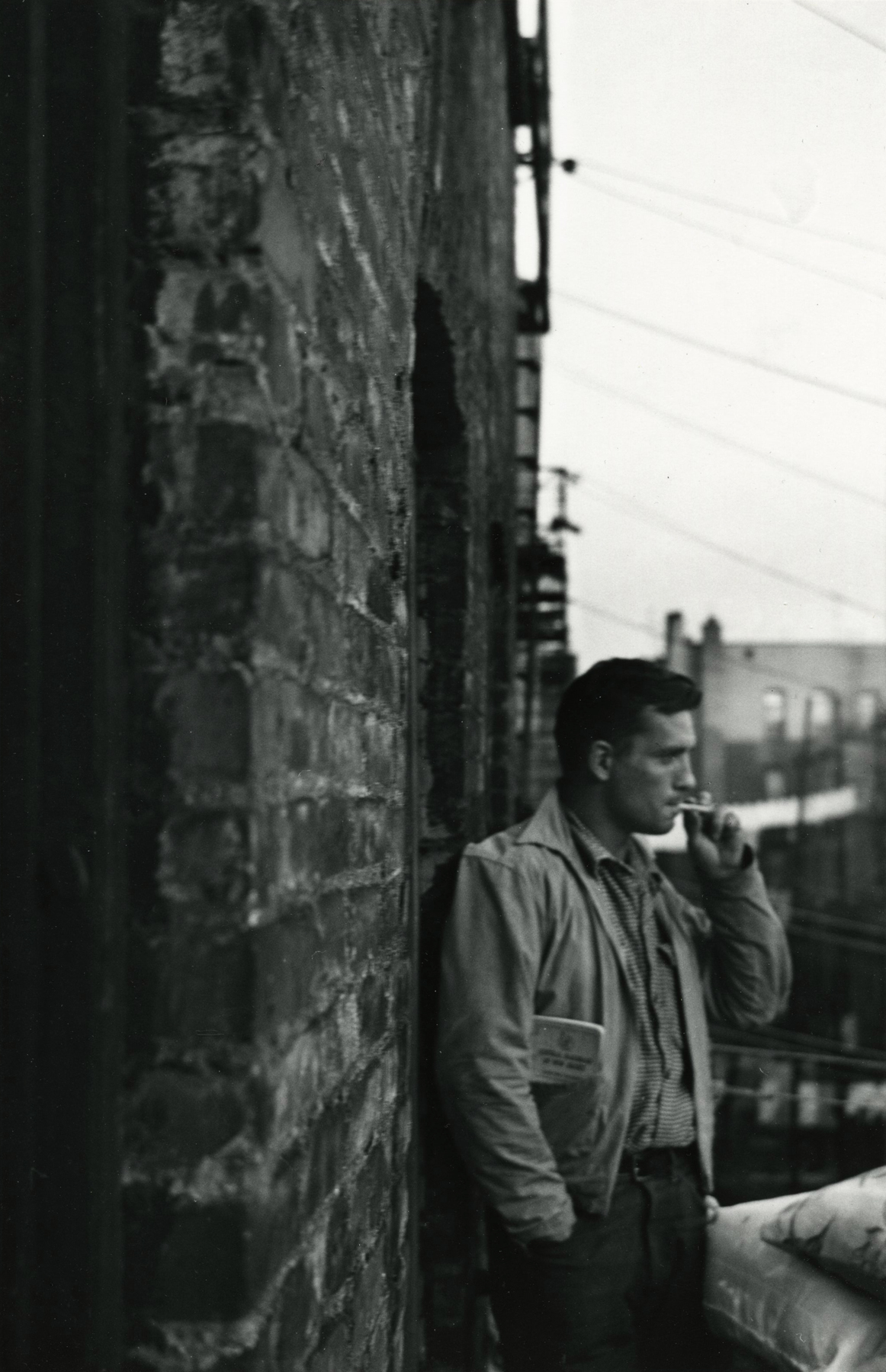 Allen Ginsberg - Heroic portrait of Jack Kerouac with R.R Brakeman's manual in pocket, fire-esape 206 E. 7th Street, NY, 16-Dec-86- Howard Greenberg Gallery
