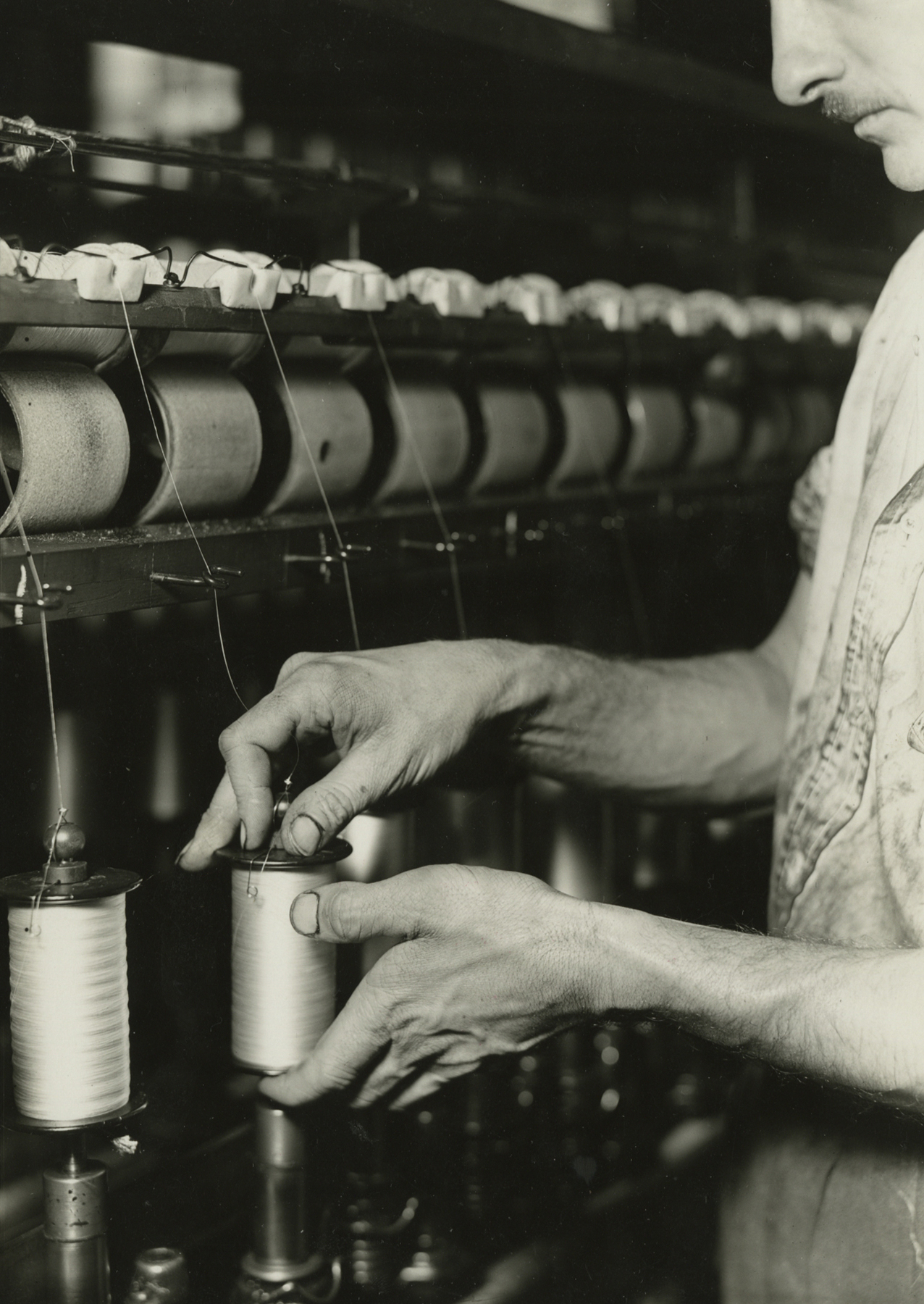 lewis hine, Rayon yarn being wound from one bobbin to another and being twisted, Paterson, New Jersey, March 18, 1937   Gelatin silver print; printed c.1937  6 5/8 x 4 5/8 inches